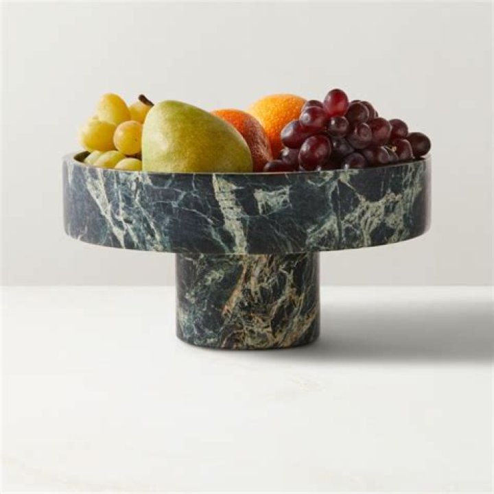 Marble board filled with fruit and cheeses.