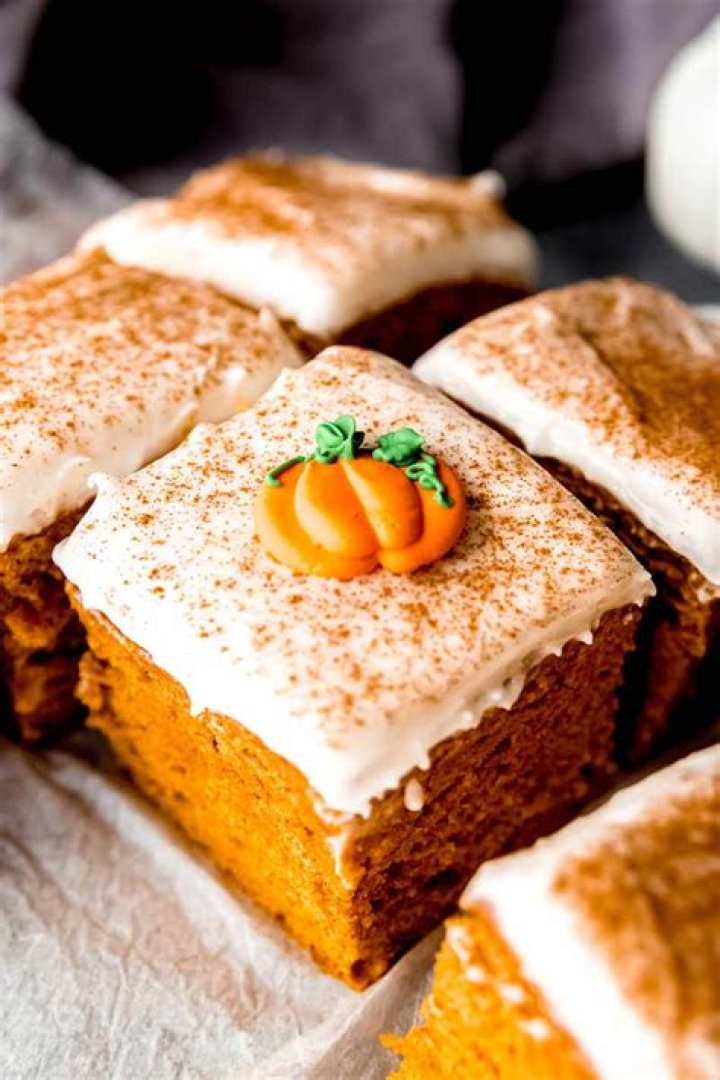 Pumpkin cake on a white plate topped with caramel and vanilla ice cream.