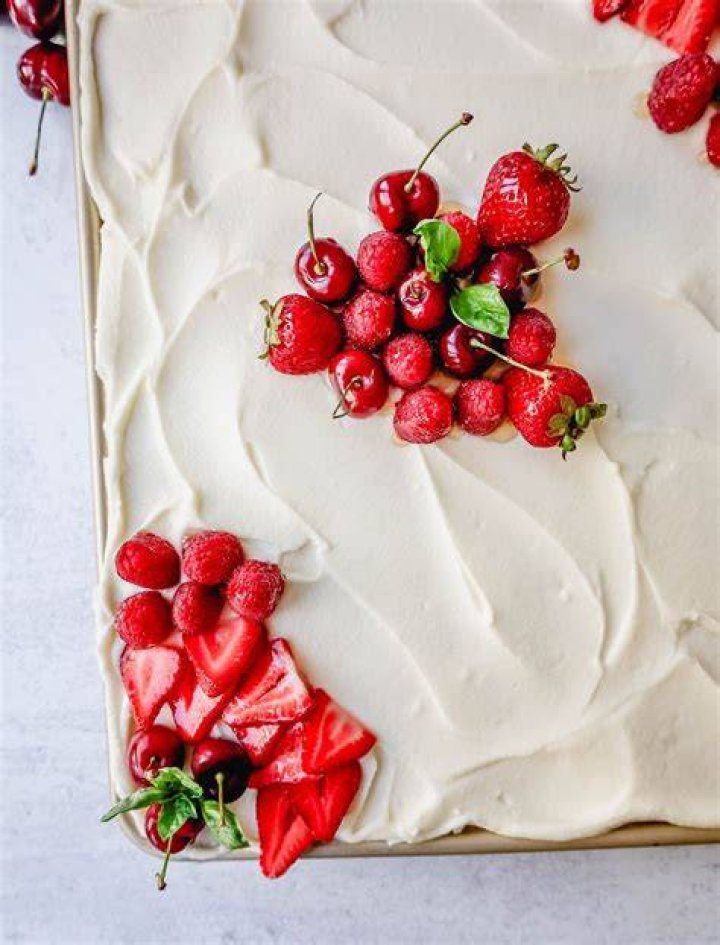 Vanilla sheet cake topped with vanilla frosting and chopped strawberries.
